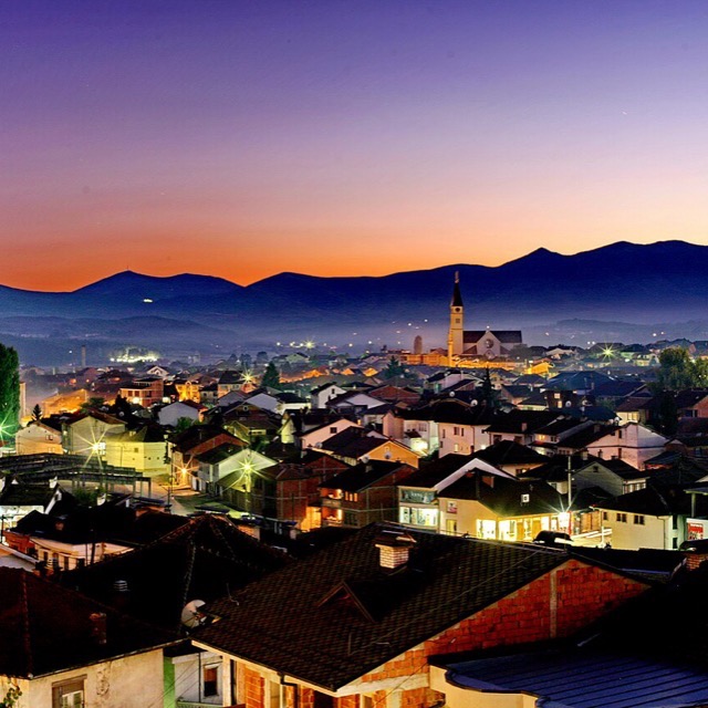 Orange dusk over a Kosovo town skyline